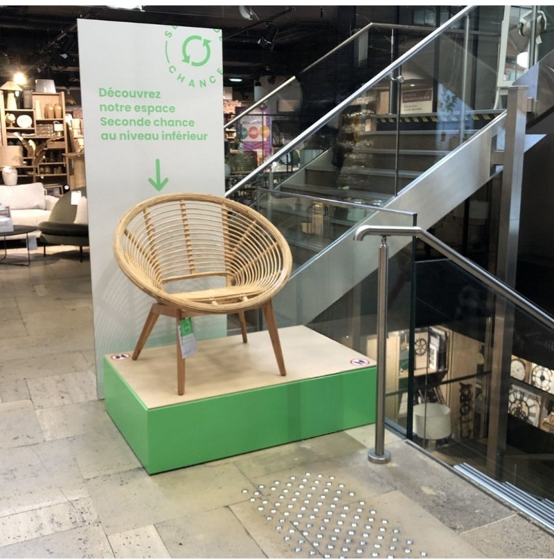 Intérieur d'un magasin de meubles avec estrade sur laquelle est posé un fauteuil d'occasion