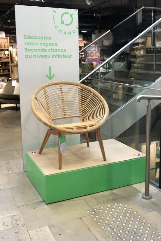 Intérieur d'un magasin de meubles avec estrade sur laquelle est posé un fauteuil d'occasion